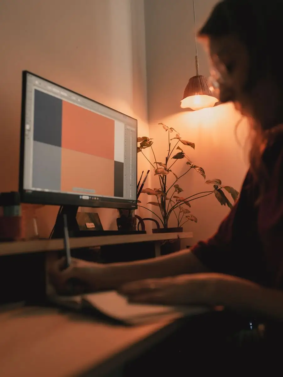 Designer working at a monitor in a studio lit by a single desk lamp